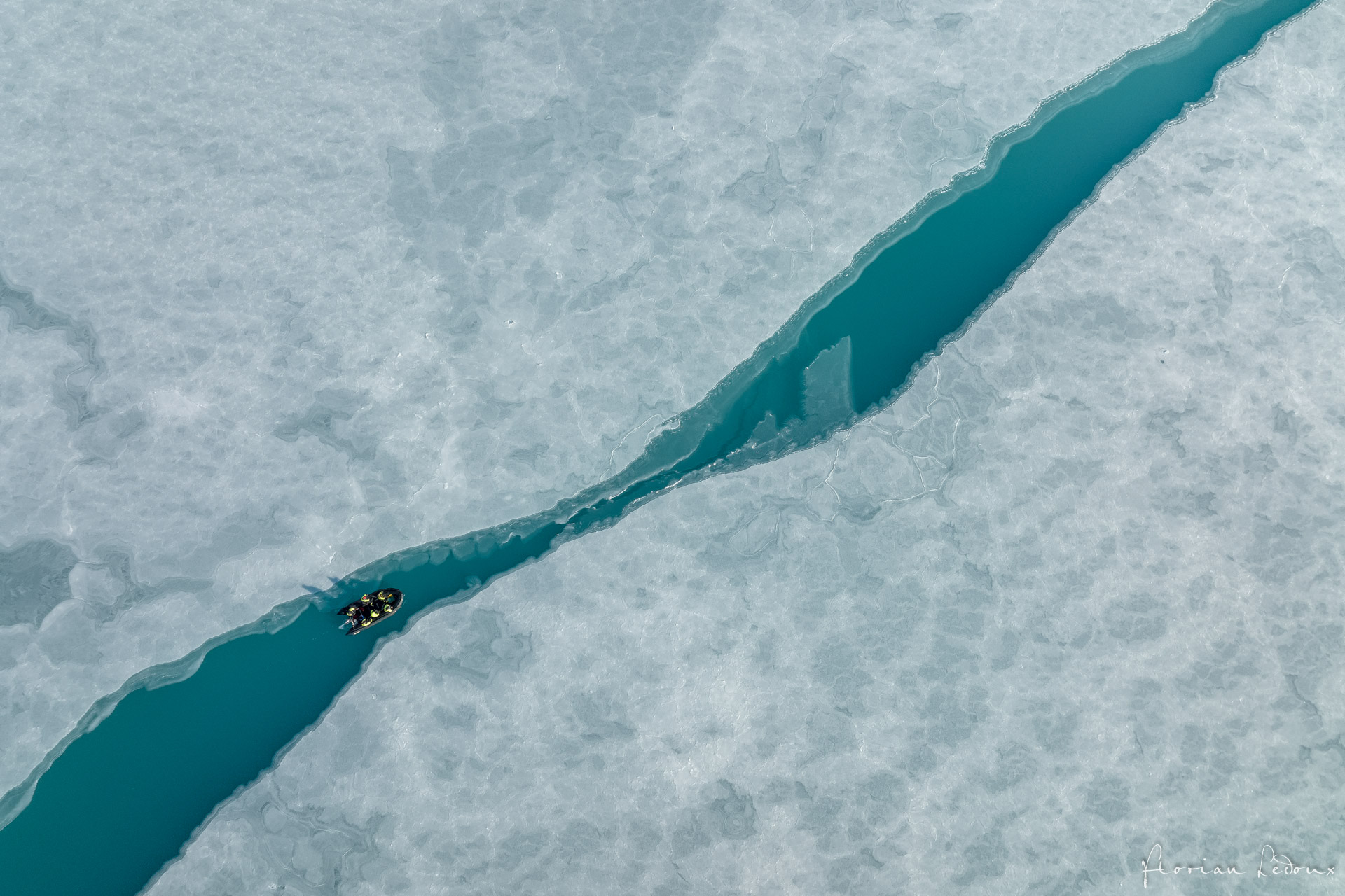 Zodiac naviguant dans un chenal turquoise au milieu de la banquise