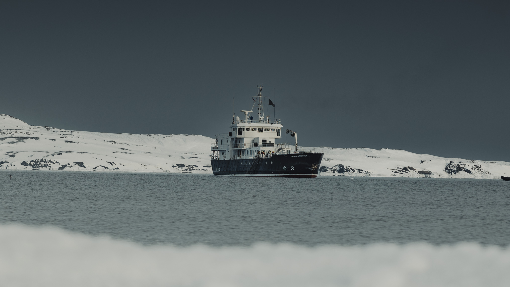 Le Grand Explorer au mouillage devant une côte enneigée du Groenland